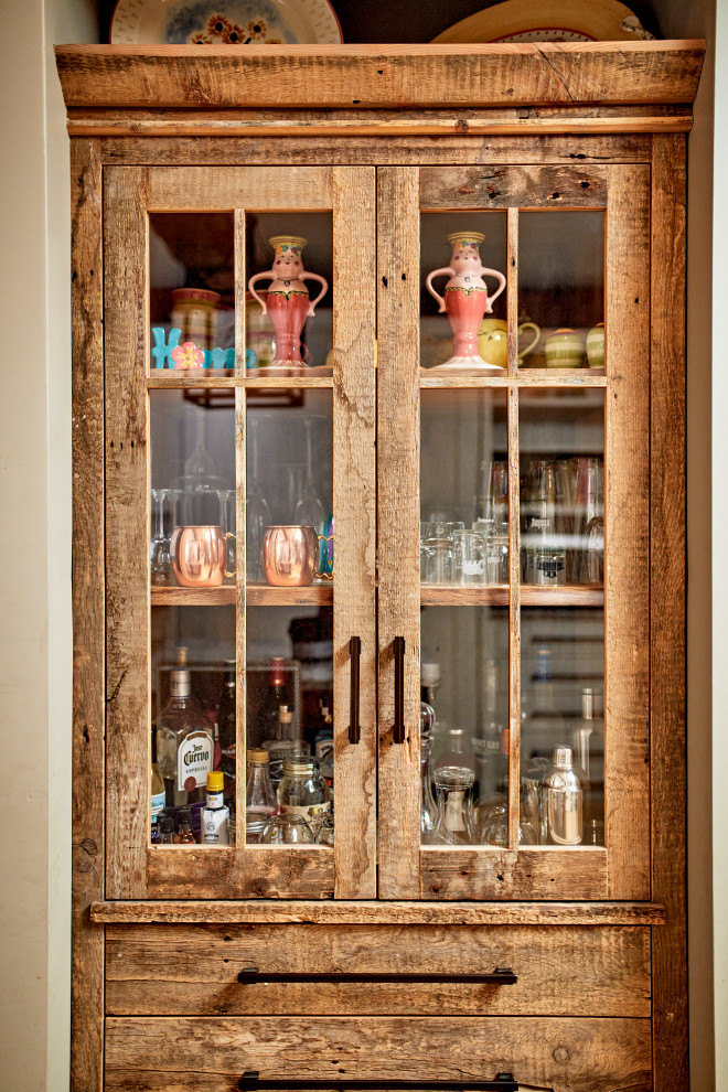 Photo of a dry bar in Portland Maine with glass-front cabinets and distressed cabinets.
