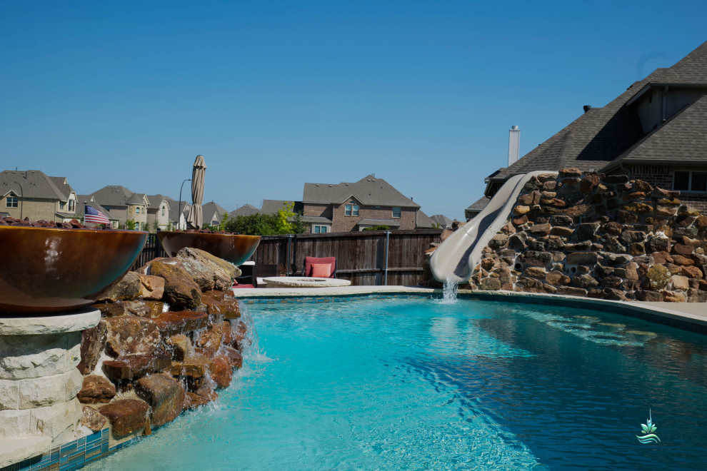 Photo of an expansive side yard custom-shaped natural pool in Dallas with a water slide and decking.