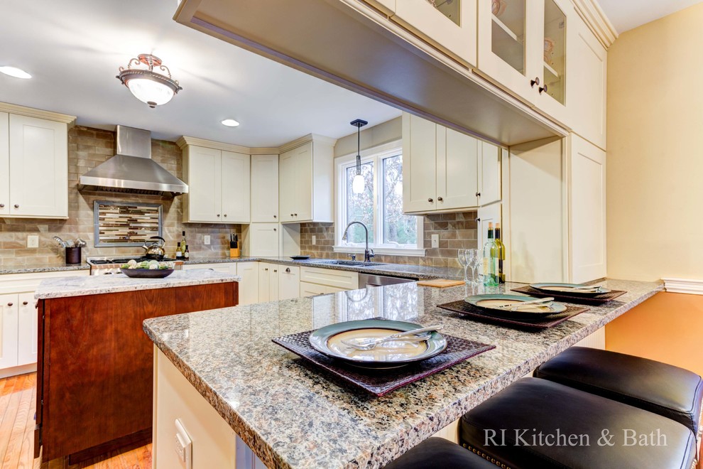 Inspiration for a large transitional u-shaped light wood floor eat-in kitchen remodel in Providence with an undermount sink, shaker cabinets, beige cabinets, granite countertops, brown backsplash, porcelain backsplash, stainless steel appliances and an island