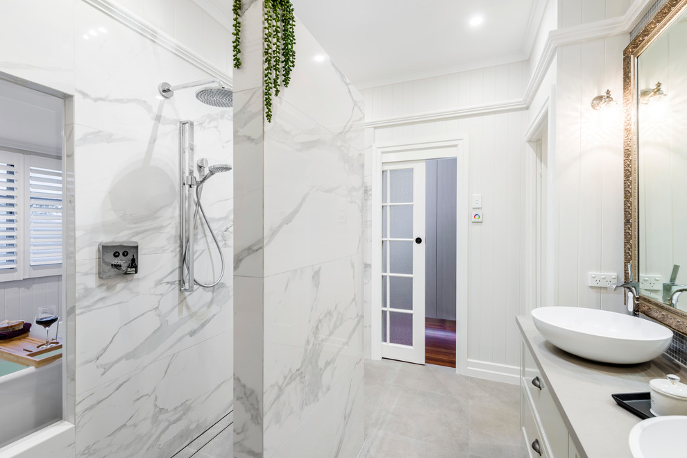 Large transitional master bathroom in Brisbane with shaker cabinets, beige cabinets, a freestanding tub, an open shower, a one-piece toilet, white tile, porcelain tile, white walls, ceramic floors, a vessel sink, engineered quartz benchtops, grey floor, an open shower and grey benchtops.