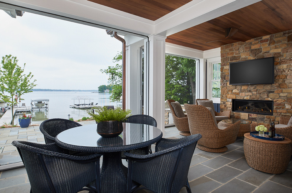 Photo of a beach style verandah in Grand Rapids with natural stone pavers, a roof extension and with fireplace.