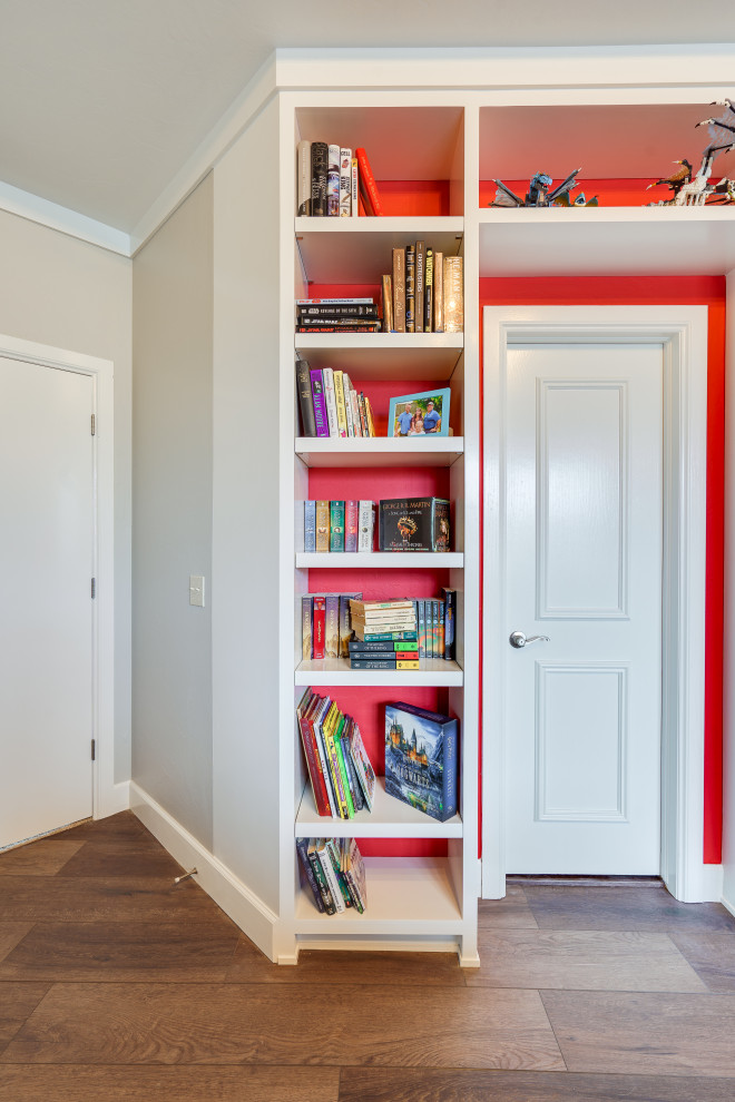 Photo of a mid-sized contemporary enclosed family room in Oklahoma City with a library, red walls, medium hardwood floors, no fireplace, a wall-mounted tv, brown floor and vaulted.