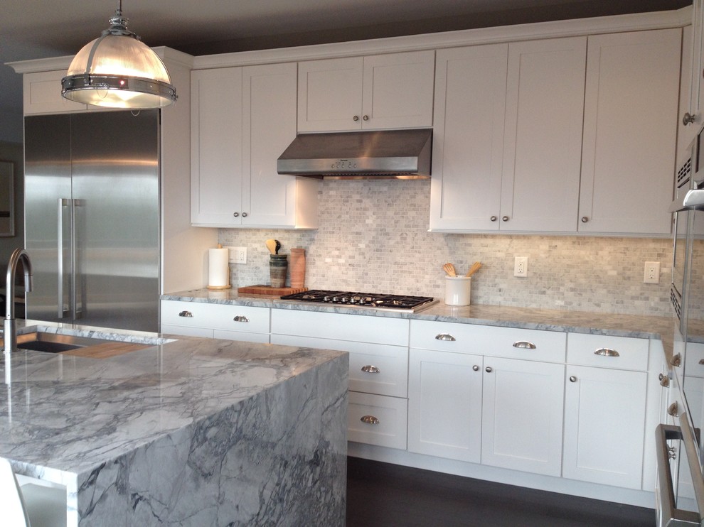 Mid-sized transitional l-shaped medium tone wood floor and gray floor eat-in kitchen photo with an undermount sink, shaker cabinets, white cabinets, marble countertops, gray backsplash, mosaic tile backsplash, stainless steel appliances and an island