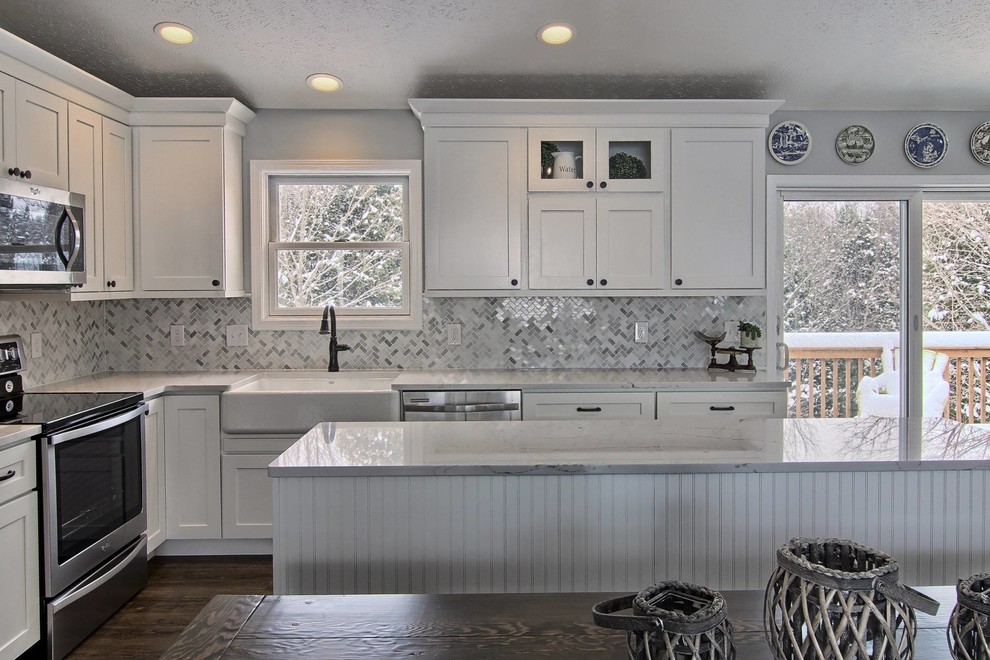 Eat-in kitchen - mid-sized transitional l-shaped vinyl floor eat-in kitchen idea with a farmhouse sink, shaker cabinets, white cabinets, quartz countertops, white backsplash, stone tile backsplash, stainless steel appliances and an island