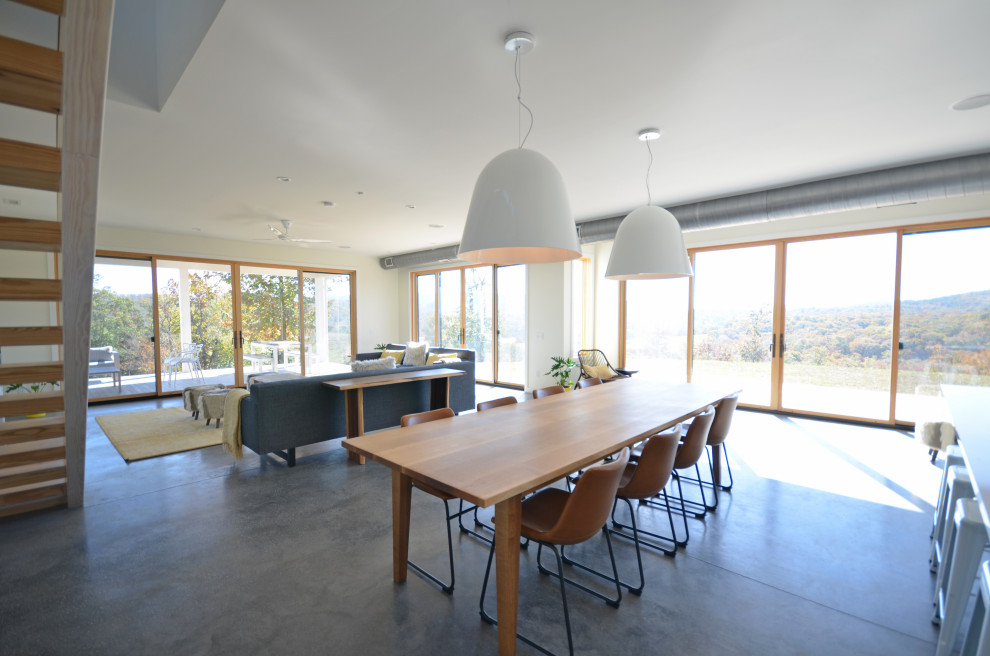 Exempel på en mellanstor modern matplats med öppen planlösning, med betonggolv, en öppen vedspis, en spiselkrans i trä, grått golv och vita väggar