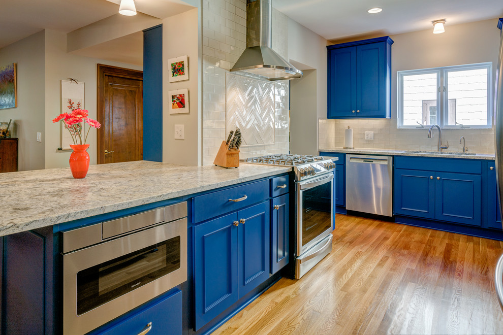 Inspiration for a transitional light wood floor kitchen remodel in Columbus with an undermount sink, recessed-panel cabinets, blue cabinets, marble countertops, white backsplash and stainless steel appliances