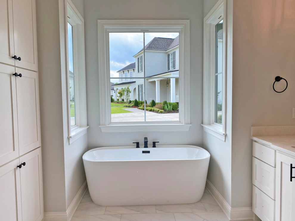 Klassisches Badezimmer En Suite mit freistehender Badewanne, Porzellan-Bodenfliesen, weißem Boden und weißer Waschtischplatte in New Orleans