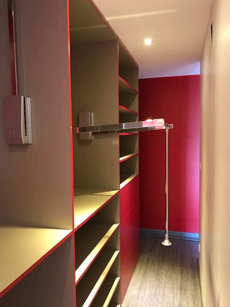 Photo of a large contemporary gender-neutral dressing room in Other with light hardwood floors, beige floor and red cabinets.