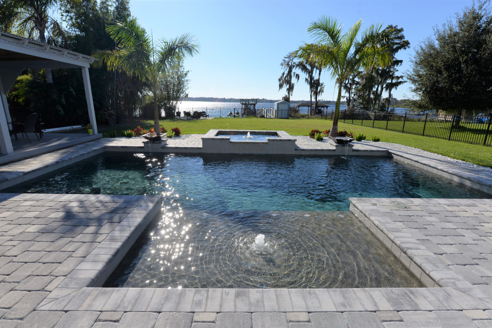 Design ideas for a large traditional backyard rectangular pool in Orlando with a pool house and brick pavers.