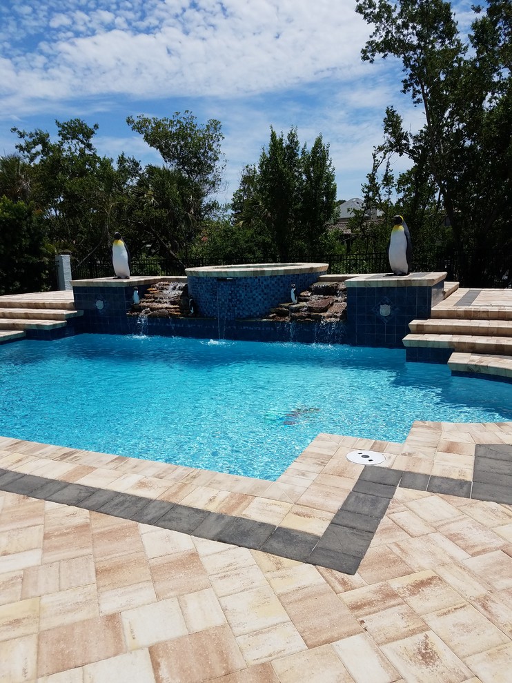 Large contemporary custom-shaped natural pool in Orlando with a hot tub and tile.