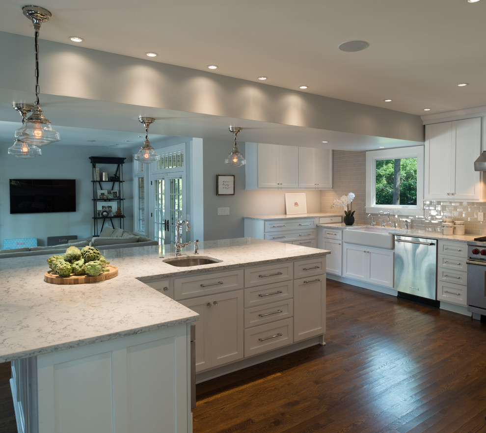 Inspiration for a country l-shaped eat-in kitchen in Indianapolis with a farmhouse sink, shaker cabinets, yellow cabinets, quartz benchtops, grey splashback, stone tile splashback, stainless steel appliances, dark hardwood floors, with island and brown floor.