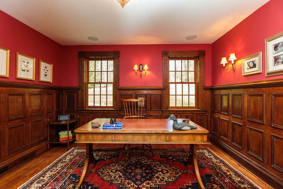 Photo of a mid-sized traditional home office in Boston with a library, red walls, medium hardwood floors and a freestanding desk.