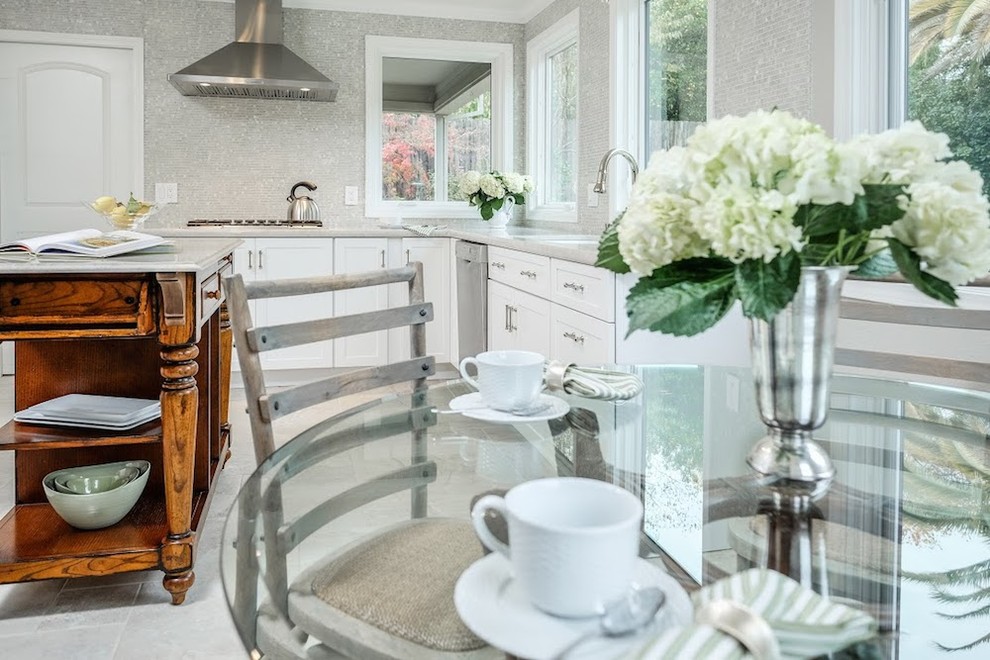 Large transitional u-shaped limestone floor eat-in kitchen photo with an undermount sink, shaker cabinets, white cabinets, marble countertops, metallic backsplash, mosaic tile backsplash, stainless steel appliances and an island