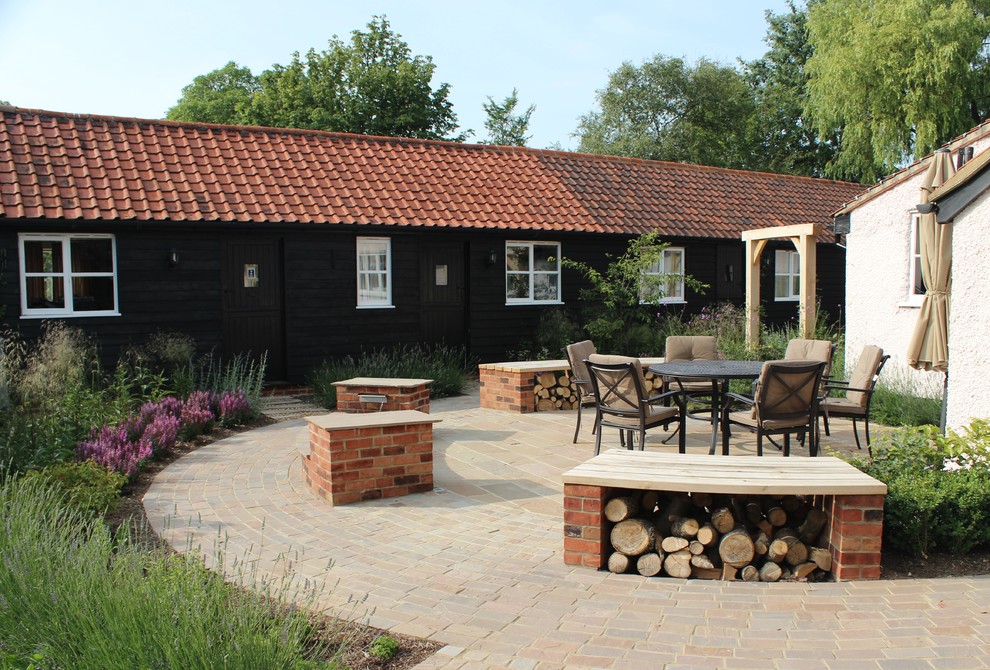 Inspiration for a mid-sized traditional backyard patio in Hertfordshire with natural stone pavers.
