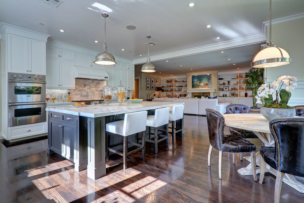 Photo of a traditional galley open plan kitchen in Los Angeles with shaker cabinets, white cabinets, white splashback, stainless steel appliances and dark hardwood floors.