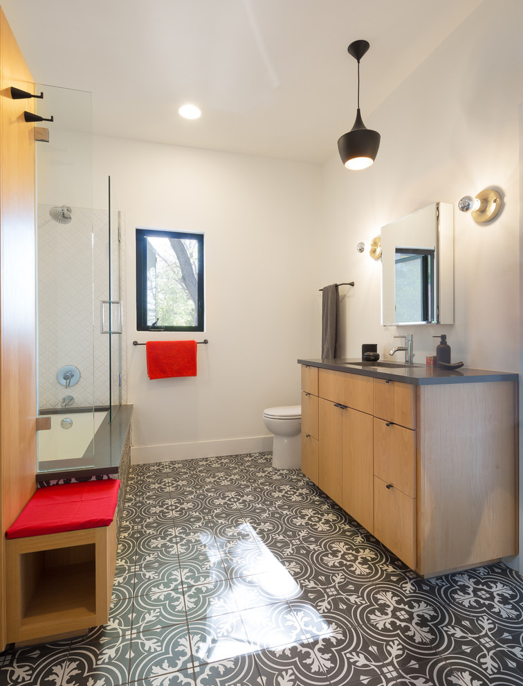 Design ideas for a mid-sized transitional master bathroom in Austin with flat-panel cabinets, light wood cabinets, an alcove shower, a one-piece toilet, black and white tile, porcelain tile, white walls, ceramic floors, an undermount sink and soapstone benchtops.