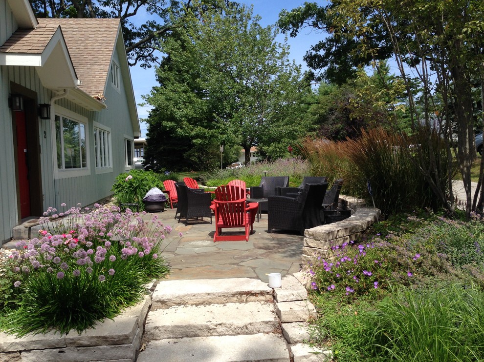 This is an example of a small beach style front yard garden for summer in Chicago with a garden path and natural stone pavers.