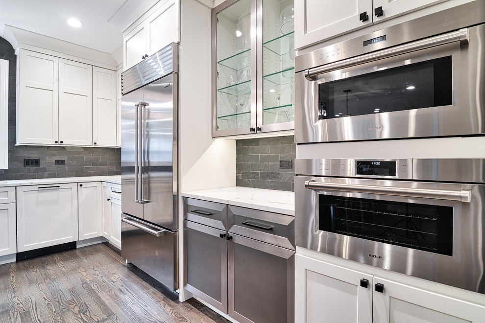 Kitchen pantry - large transitional u-shaped medium tone wood floor and brown floor kitchen pantry idea in Nashville with an undermount sink, shaker cabinets, dark wood cabinets, solid surface countertops, black backsplash, brick backsplash, stainless steel appliances, an island and white countertops
