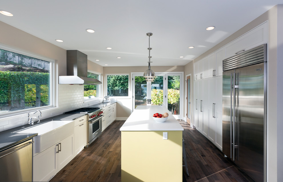 Kitchen - transitional kitchen idea in Seattle with a farmhouse sink, shaker cabinets, white cabinets, white backsplash, subway tile backsplash and stainless steel appliances