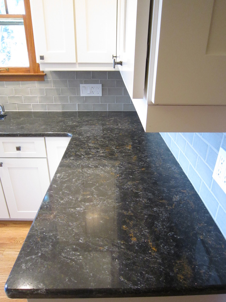 Inspiration for a mid-sized transitional l-shaped light wood floor eat-in kitchen remodel in Chicago with shaker cabinets, gray backsplash, subway tile backsplash, no island, white cabinets, an undermount sink, granite countertops and stainless steel appliances
