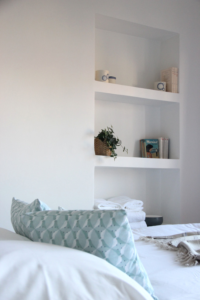 Scandinavian bedroom in Marseille with white walls and terra-cotta floors.