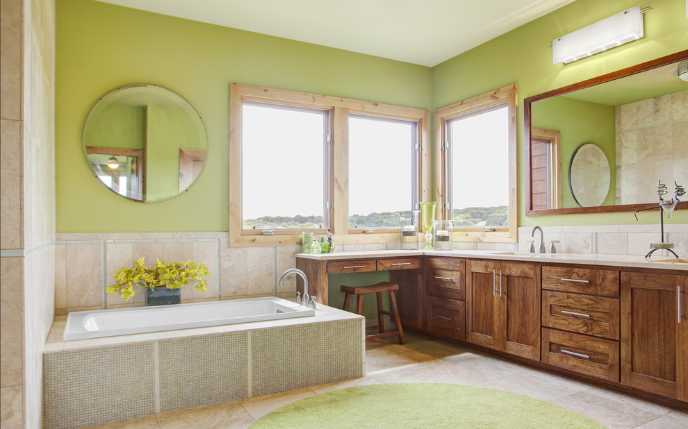 This is an example of a mid-sized contemporary bathroom in Austin with medium wood cabinets, a drop-in tub, beige tile, travertine, green walls, travertine floors, beige floor, beige benchtops, a double vanity and a built-in vanity.