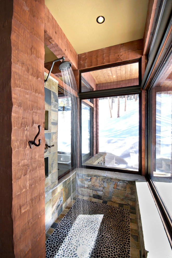 Example of a small mountain style stone tile and gray tile pebble tile floor doorless shower design with multicolored walls