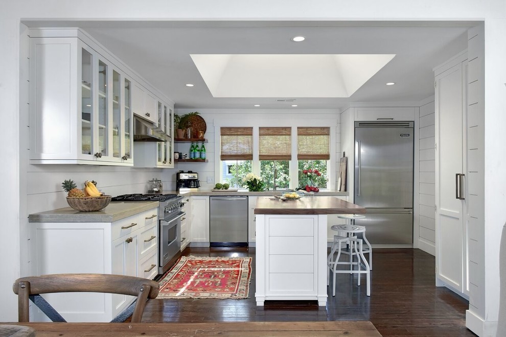 Inspiration for a large beach style u-shaped eat-in kitchen in Charleston with a farmhouse sink, shaker cabinets, white cabinets, limestone benchtops, white splashback, stainless steel appliances, dark hardwood floors and with island.