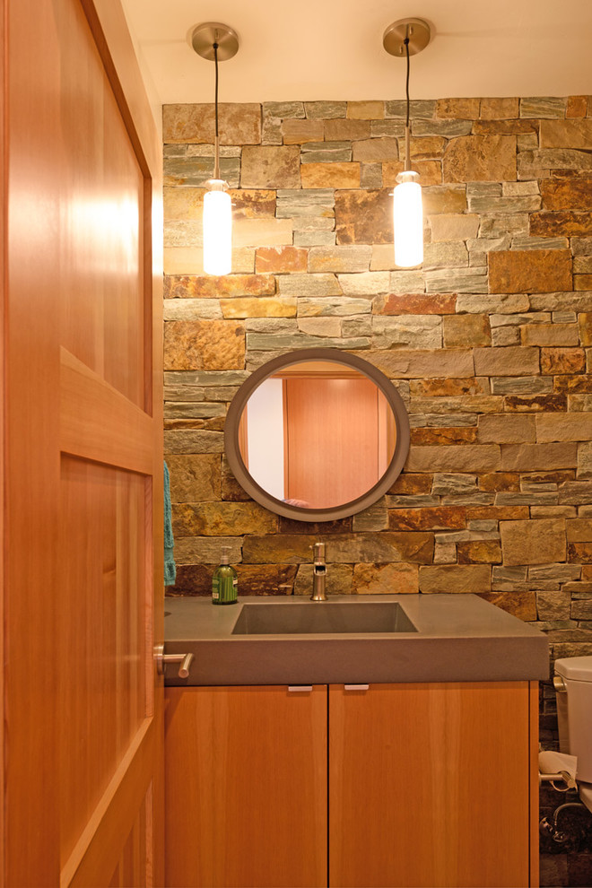 Mid-sized modern powder room in Other with flat-panel cabinets, medium wood cabinets, a one-piece toilet, gray tile, stone tile, grey walls, bamboo floors, an integrated sink, concrete benchtops, beige floor and grey benchtops.