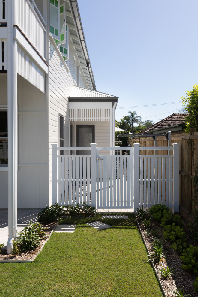 Photo of a transitional courtyard full sun garden in Brisbane with with a gate, natural stone pavers and a metal fence.