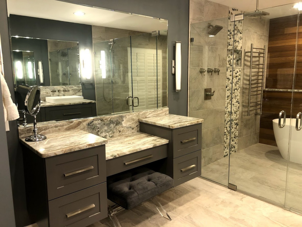 Design ideas for a mid-sized transitional master wet room bathroom in Baltimore with shaker cabinets, grey cabinets, a freestanding tub, a one-piece toilet, gray tile, porcelain tile, blue walls, porcelain floors, a vessel sink, granite benchtops, grey floor, a hinged shower door, multi-coloured benchtops, an enclosed toilet, a double vanity and a floating vanity.