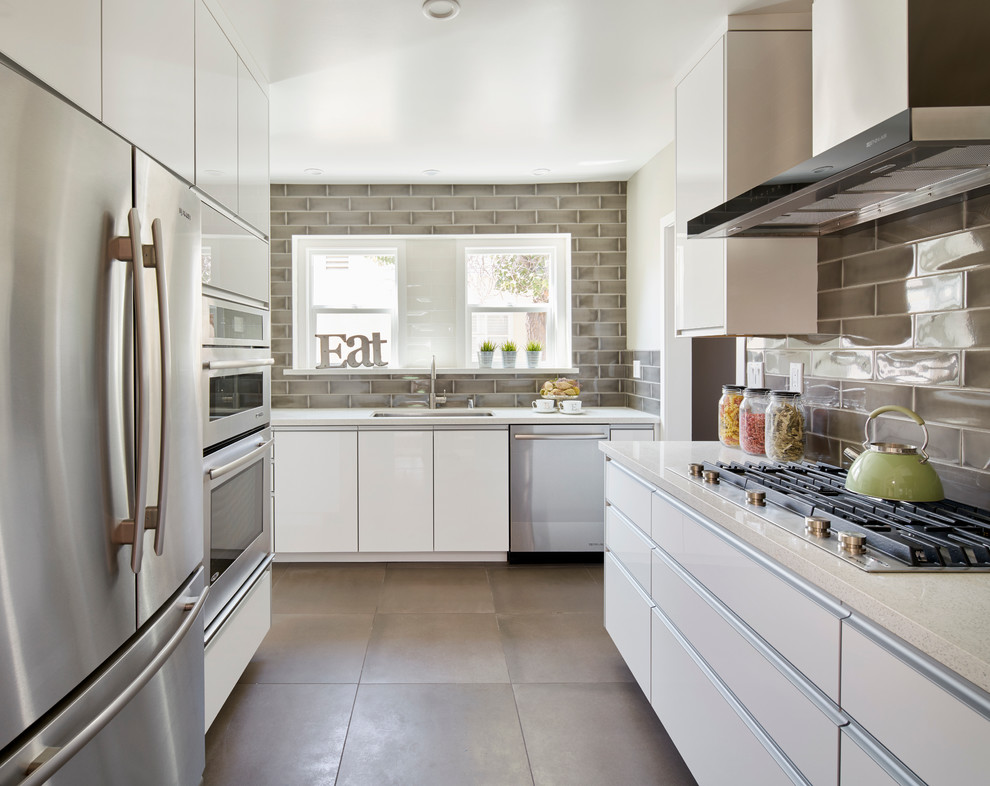 Contemporary u-shaped kitchen in Los Angeles with an undermount sink, flat-panel cabinets, white cabinets, grey splashback, subway tile splashback and stainless steel appliances.