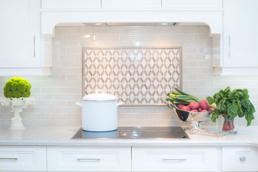 Example of a mid-sized transitional u-shaped eat-in kitchen design in Toronto with shaker cabinets, white cabinets, white backsplash, an island, quartz countertops and stainless steel appliances