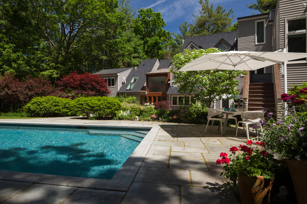 This is an example of an expansive transitional backyard patio in Boston with natural stone pavers and no cover.