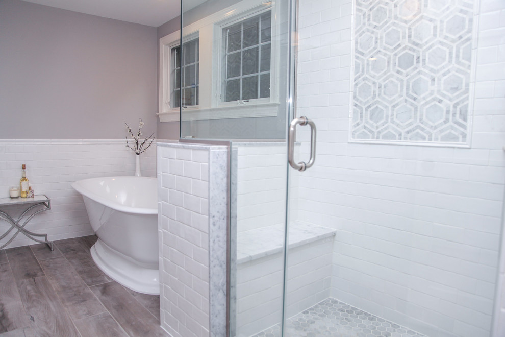 Photo of a mid-sized traditional master bathroom in New York with shaker cabinets, white cabinets, white tile, subway tile, a freestanding tub, a corner shower, grey walls, porcelain floors, an integrated sink and solid surface benchtops.