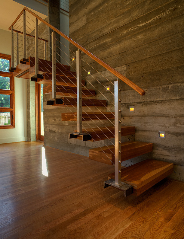 This is an example of a small modern wood straight staircase in Charlotte with open risers and cable railing.
