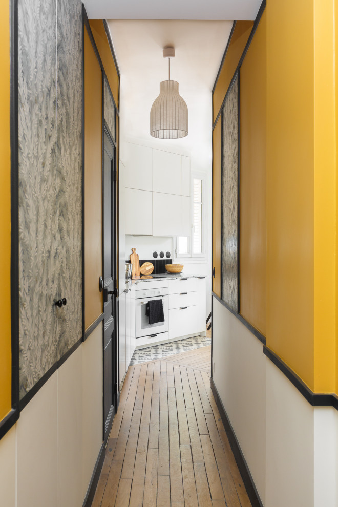 Mittelgroßer Retro Eingang mit Korridor, gelber Wandfarbe, hellem Holzboden und Tapetenwänden in Paris