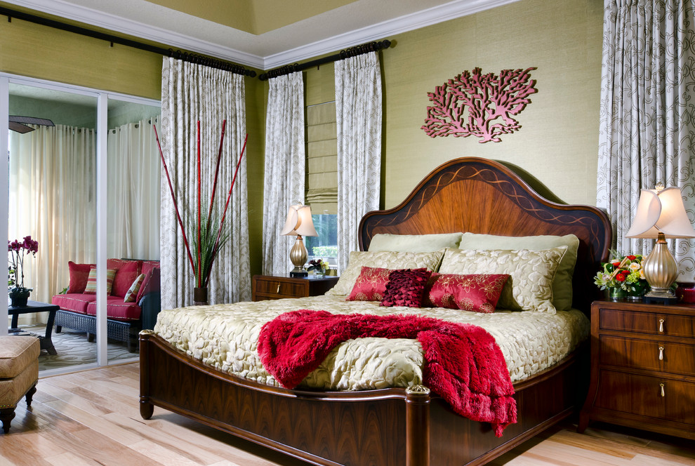 Design ideas for a large tropical master bedroom in Miami with green walls and light hardwood floors.