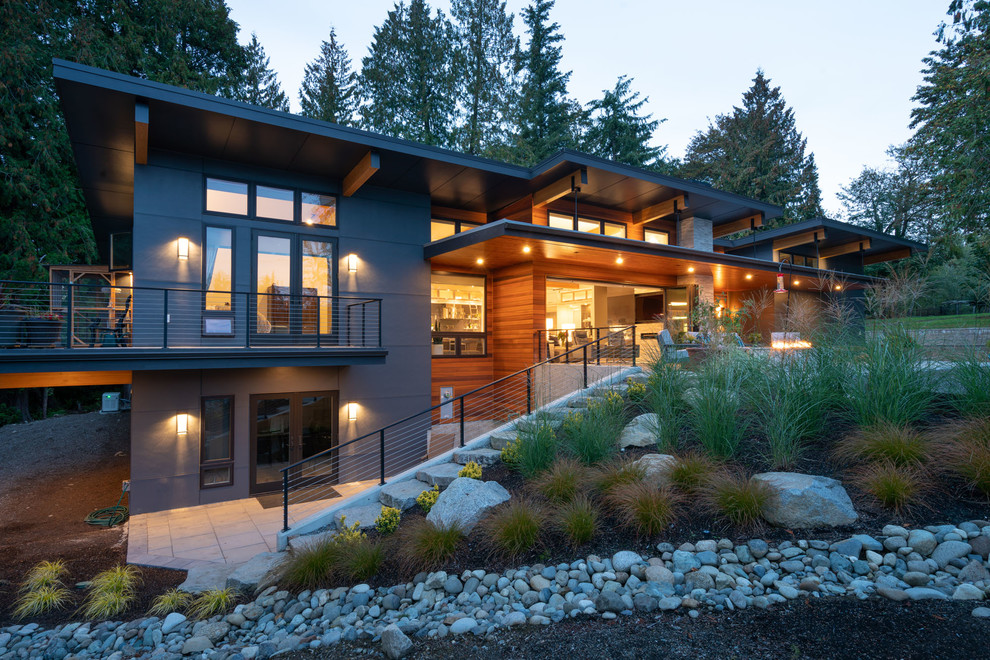 This is an example of a contemporary two-storey grey house exterior in Seattle with concrete fiberboard siding, a shed roof and a metal roof.