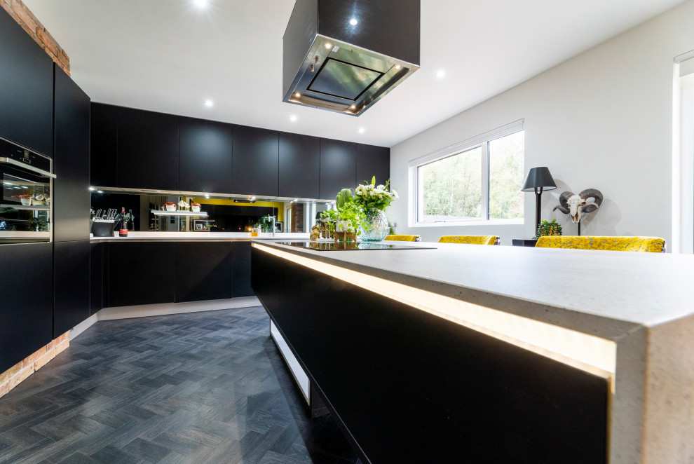 Photo of a mid-sized contemporary l-shaped eat-in kitchen in Edinburgh with a drop-in sink, flat-panel cabinets, black cabinets, solid surface benchtops, grey splashback, mirror splashback, black appliances, dark hardwood floors, with island, black floor and multi-coloured benchtop.