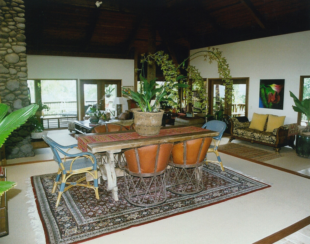 Expansive tropical dining room in San Francisco with white walls, carpet and a stone fireplace surround.