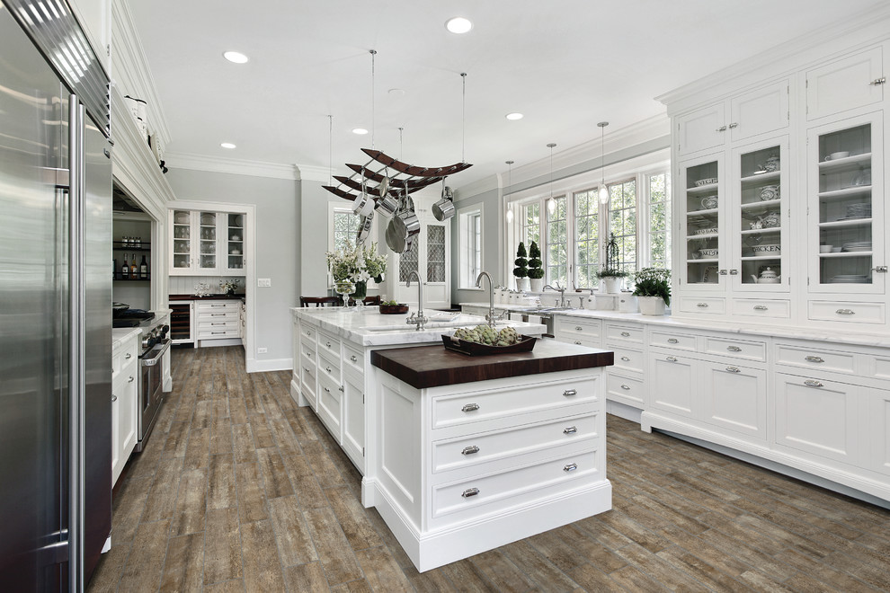 Expansive country u-shaped separate kitchen in Philadelphia with a farmhouse sink, shaker cabinets, white cabinets, quartzite benchtops, stainless steel appliances, vinyl floors and with island.