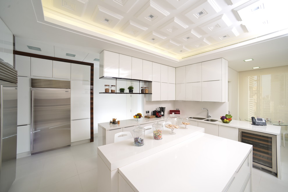Photo of a contemporary kitchen in Other with white cabinets, quartz benchtops, white splashback, stainless steel appliances, porcelain floors and white floor.