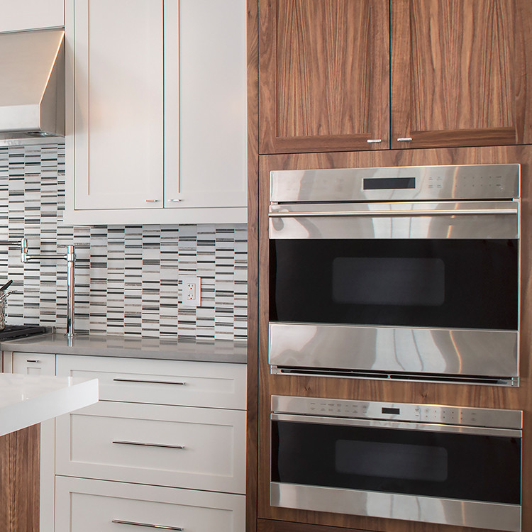 Example of a mid-sized transitional l-shaped dark wood floor eat-in kitchen design in Toronto with a double-bowl sink, shaker cabinets, white cabinets, solid surface countertops, multicolored backsplash, mosaic tile backsplash, stainless steel appliances and an island