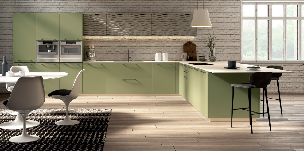 Ispirazione per una grande cucina a L minimalista con ante verdi, paraspruzzi in mattoni, elettrodomestici in acciaio inossidabile, parquet chiaro e top bianco