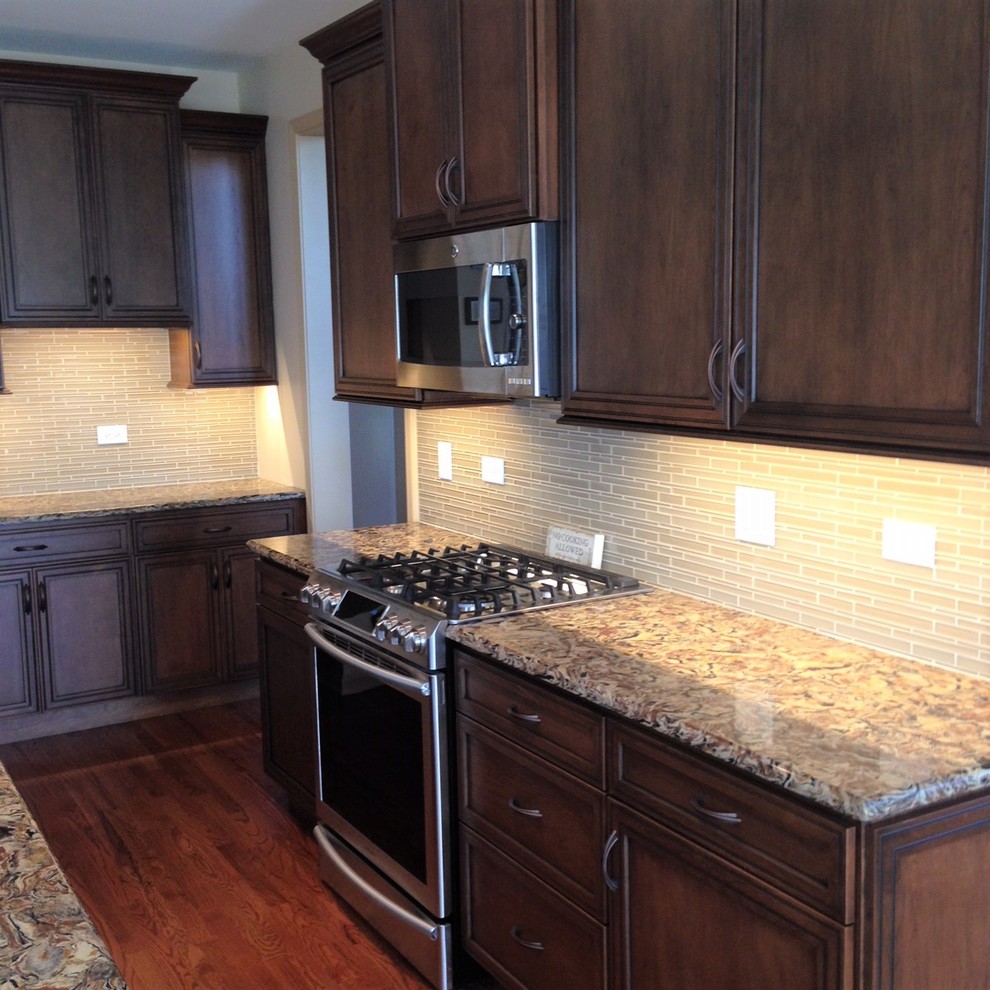 Mid-sized transitional medium tone wood floor and brown floor eat-in kitchen photo in Chicago with a double-bowl sink, recessed-panel cabinets, medium tone wood cabinets, quartz countertops, beige backsplash, glass sheet backsplash, stainless steel appliances and an island