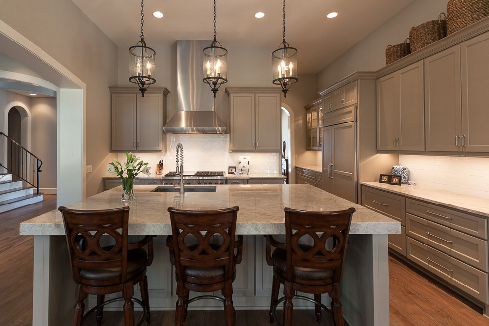 Design ideas for a large transitional l-shaped open plan kitchen in Houston with a drop-in sink, recessed-panel cabinets, beige cabinets, granite benchtops, white splashback, subway tile splashback, stainless steel appliances, light hardwood floors and with island.