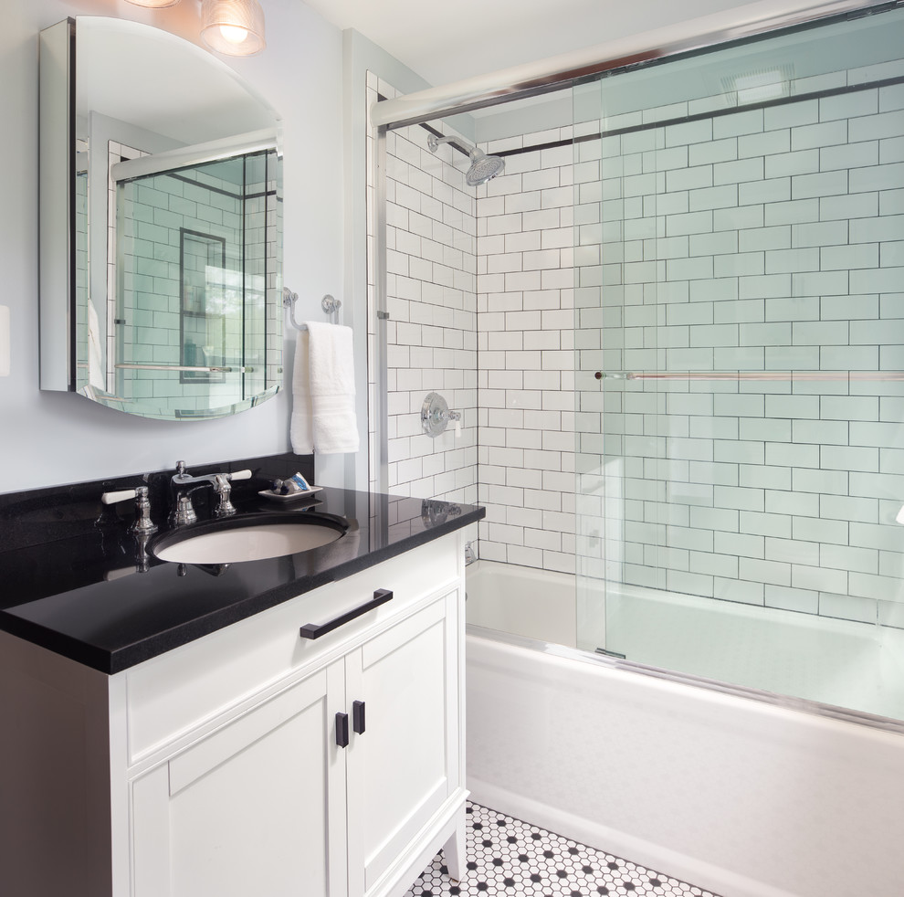 Photo of a mid-sized traditional bathroom in DC Metro with furniture-like cabinets, white cabinets, an alcove tub, an alcove shower, a two-piece toilet, white tile, subway tile, grey walls, ceramic floors, an undermount sink, granite benchtops, a sliding shower screen and black benchtops.