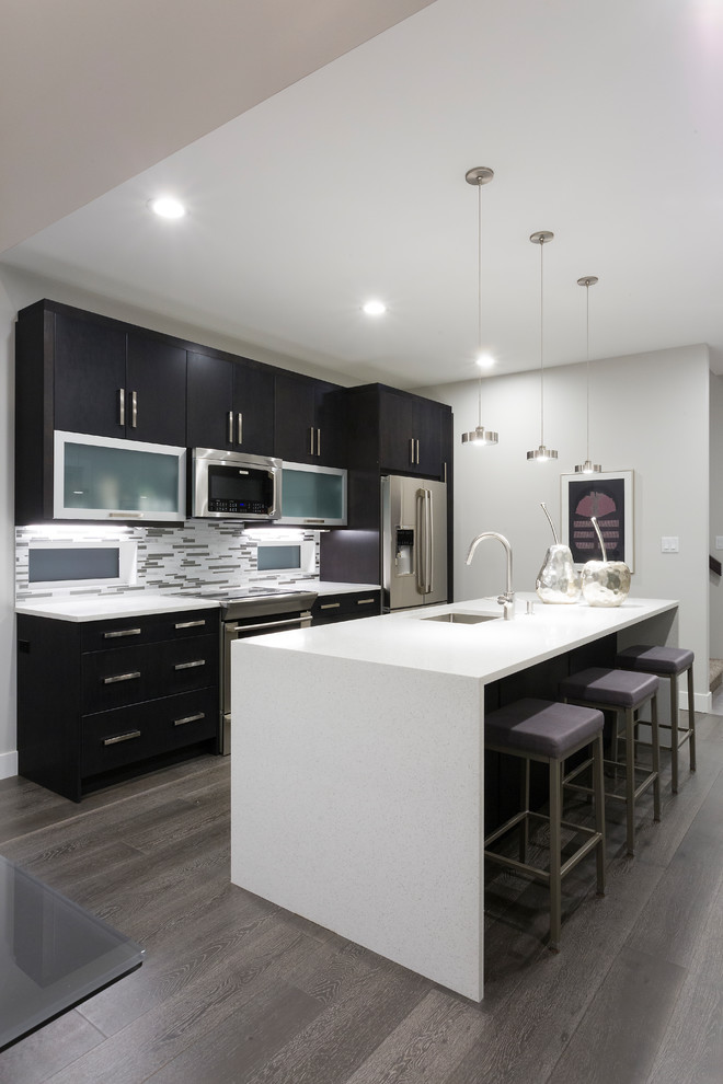Inspiration for a small contemporary galley eat-in kitchen in Other with an undermount sink, flat-panel cabinets, dark wood cabinets, quartzite benchtops, glass tile splashback, stainless steel appliances, light hardwood floors and with island.