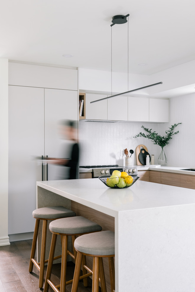 Inspiration for a small scandi l-shaped kitchen/diner in Toronto with a submerged sink, flat-panel cabinets, light wood cabinets, engineered stone countertops, white splashback, ceramic splashback, stainless steel appliances, dark hardwood flooring, an island, brown floors and beige worktops.